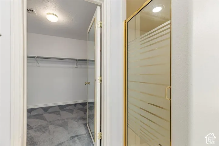 Walk-in closet with geometric patterned carpet and shelf storage