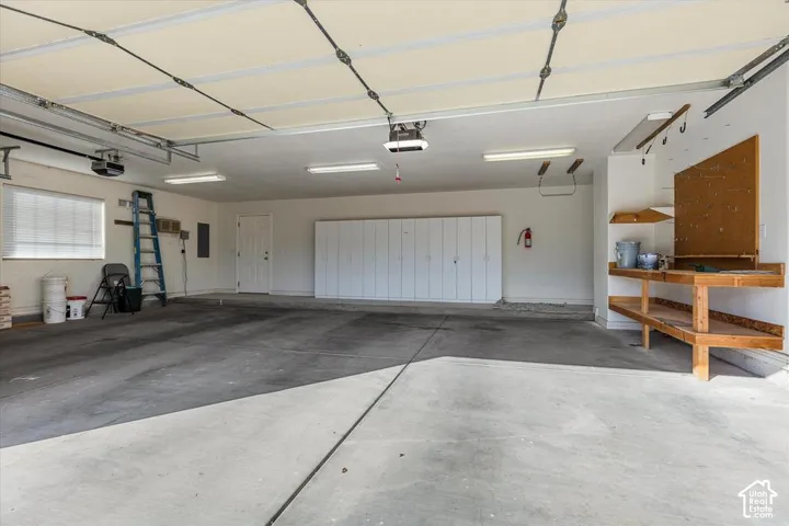 Spacious garage with overhead lighting, built-in cabinetry, and a dedicated workbench area