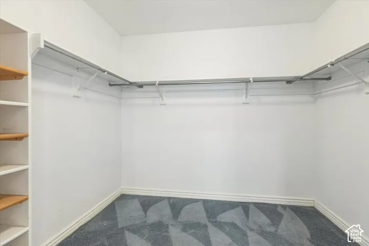 Walk-in closet with integrated shelving, L-shaped hanging rods, and patterned carpeting