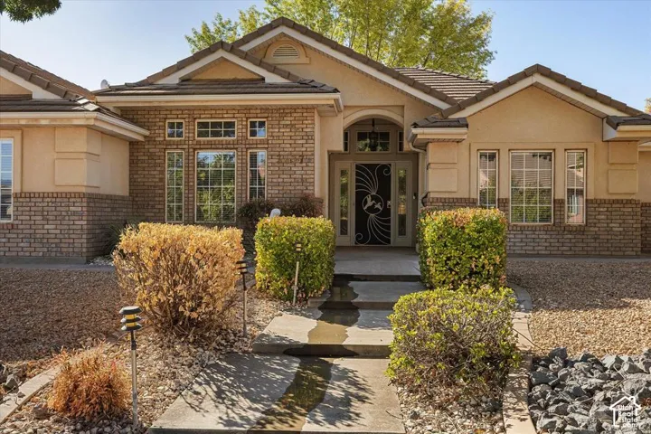 Stucco and brick facade with decorative window grilles, arched entry, and a tiled roof