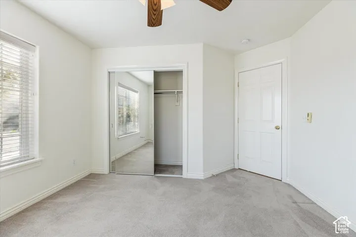 Plush carpeting, window with horizontal blinds, wood-finish ceiling fan, mirrored sliding closet doors, and a six-panel door
