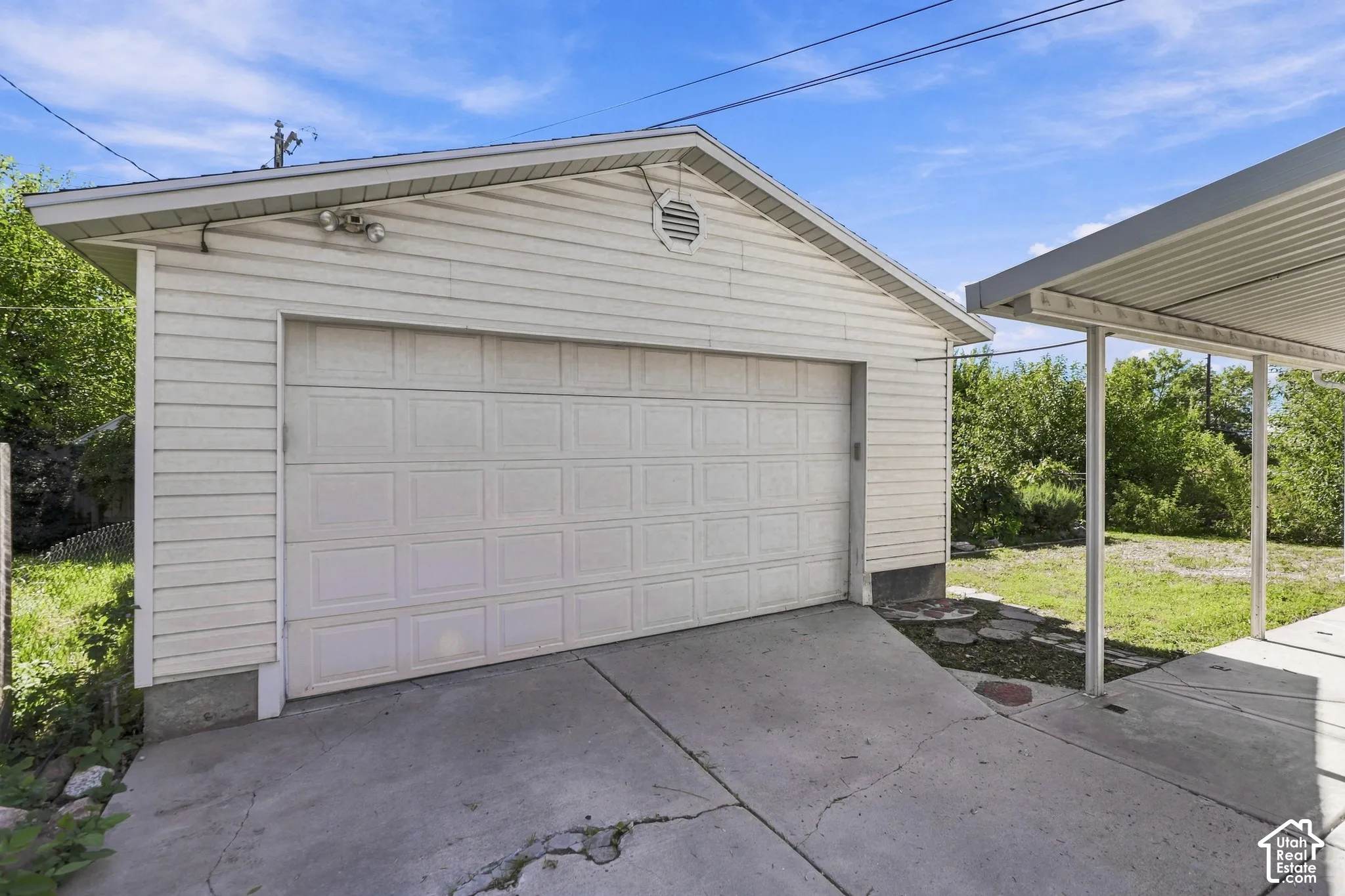 Detached garage with horizontal siding, a paneled garage door, and a concrete driveway