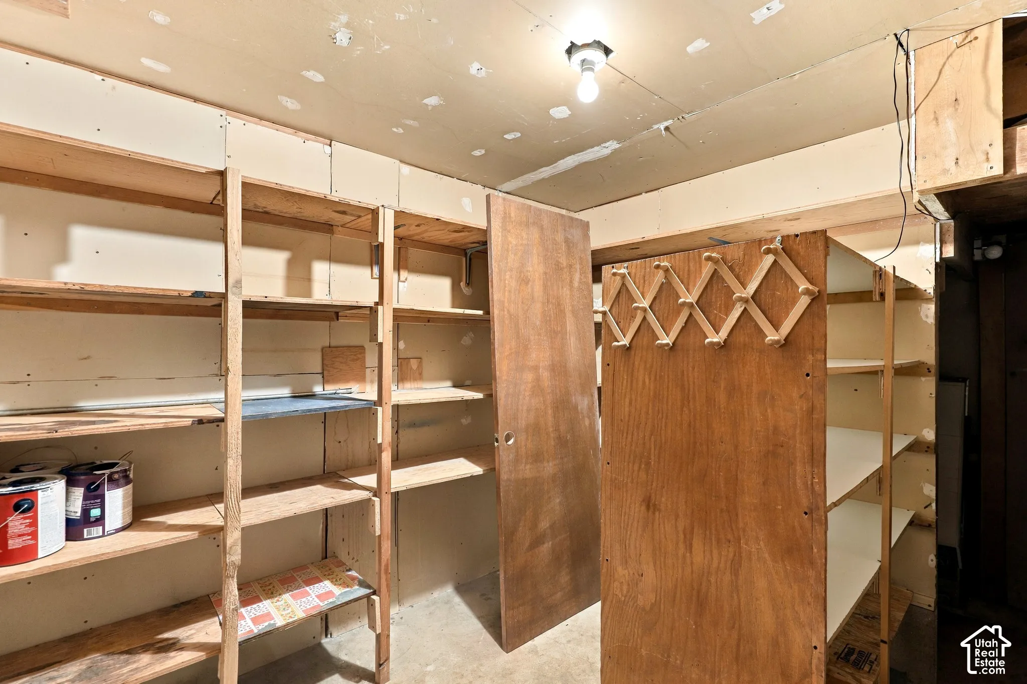 Extensive built-in shelving, exposed bulb ceiling light fixture, wood-finish paneling, concrete flooring