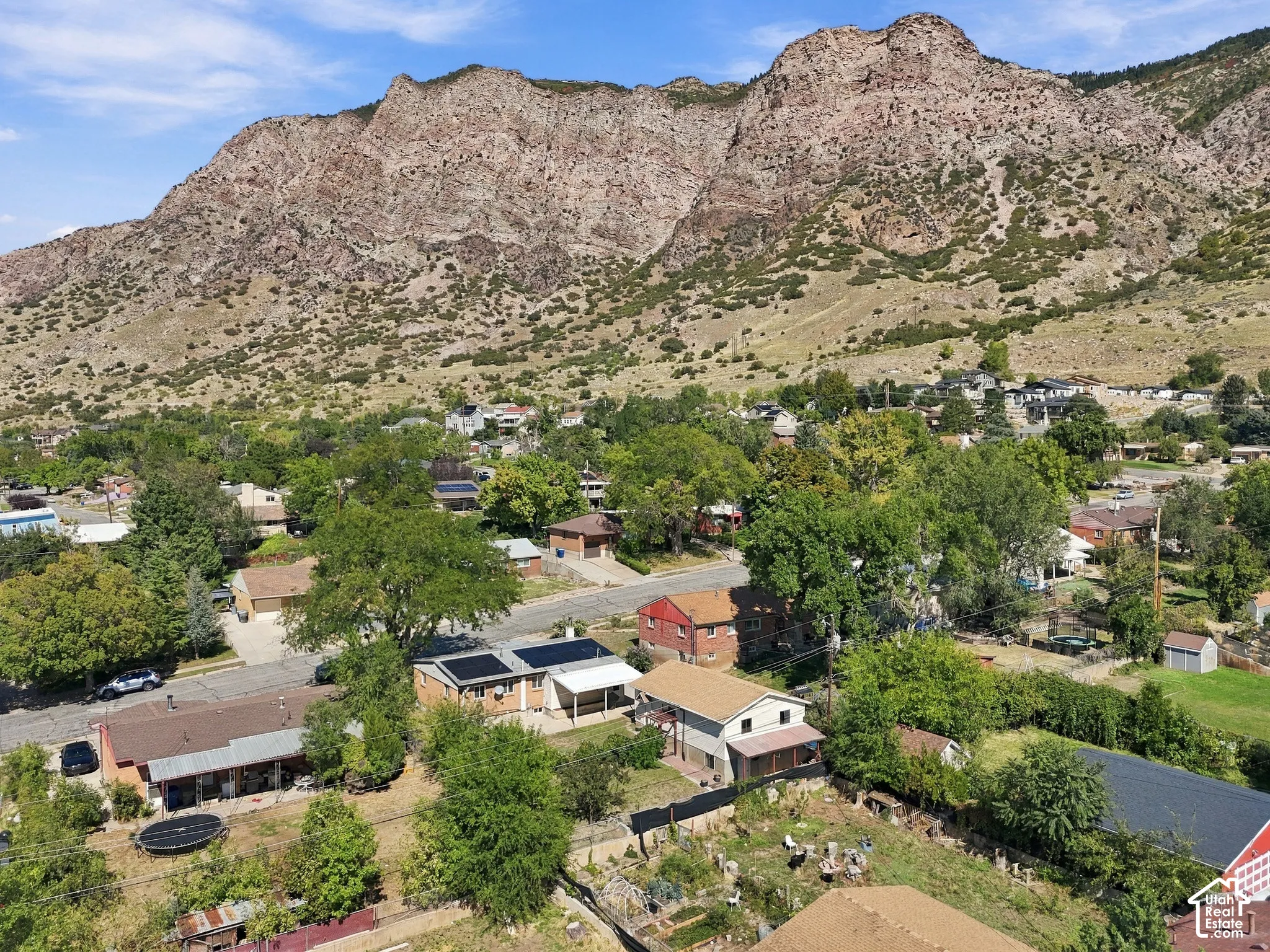 Mountainous backdrop, residential neighborhood, mature trees, paved streets, solar panel installation