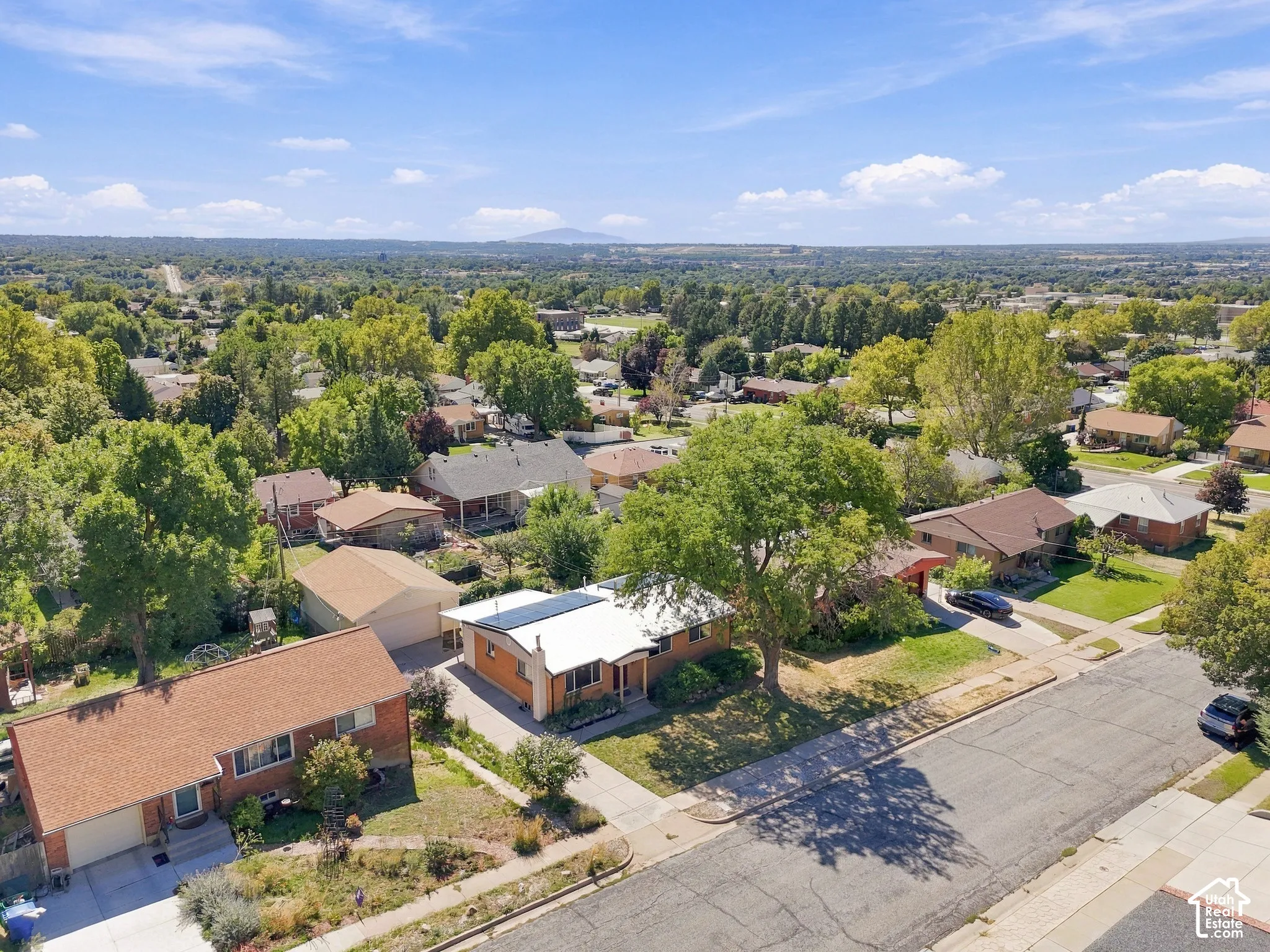 Neighborhood setting with mature trees, paved streets, and residential rooftops