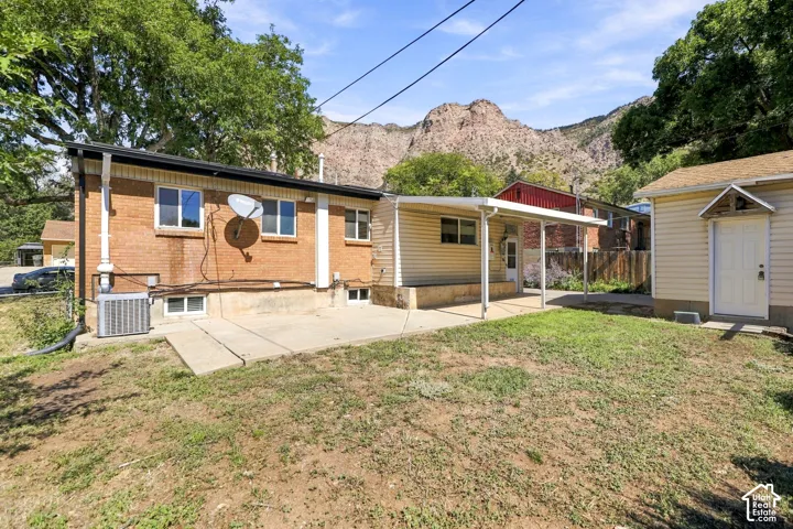 Brick exterior, rear patio, covered walkway, separate storage structure, mountain backdrop