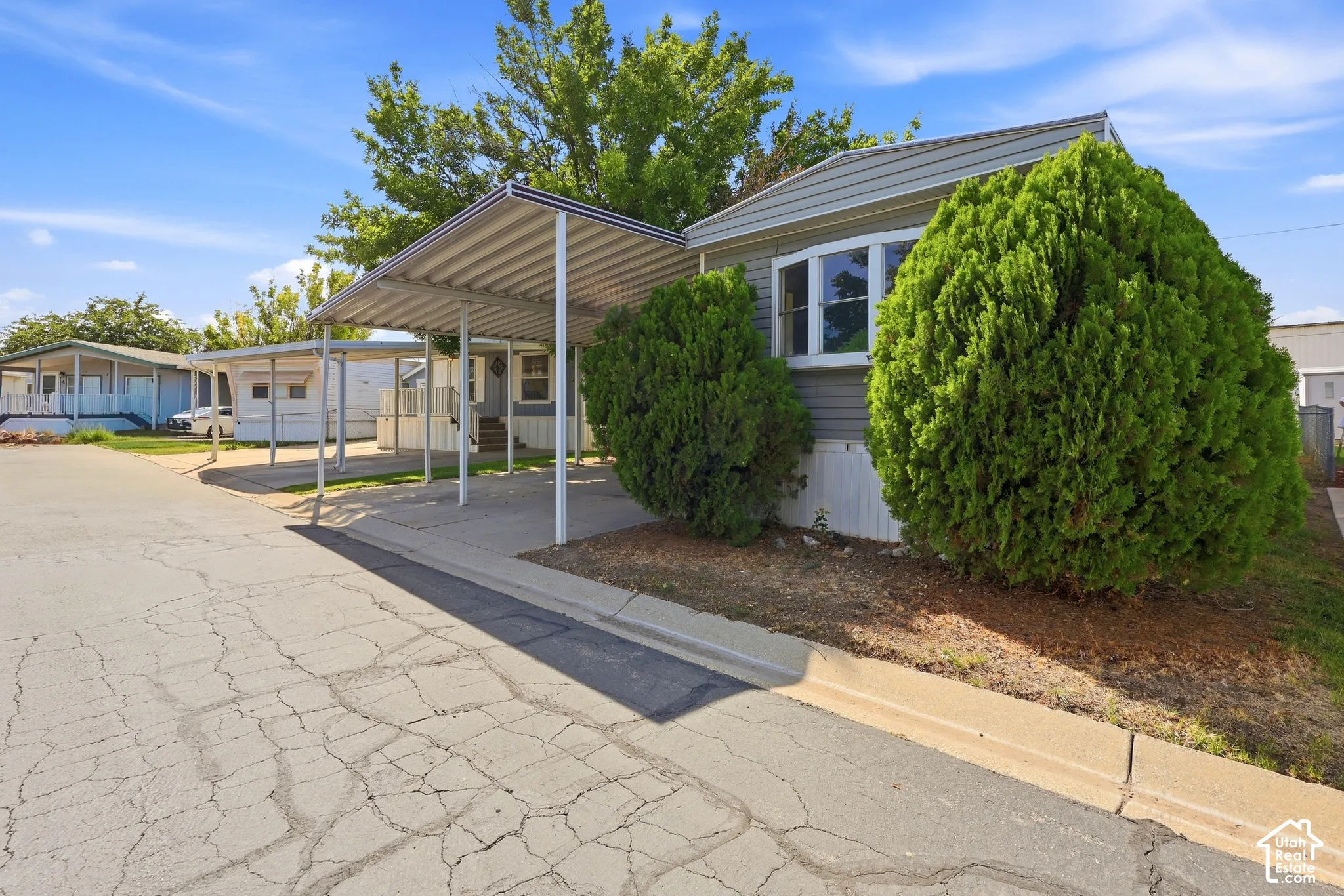 Siding exterior with a bay window, covered carport, and established landscaping