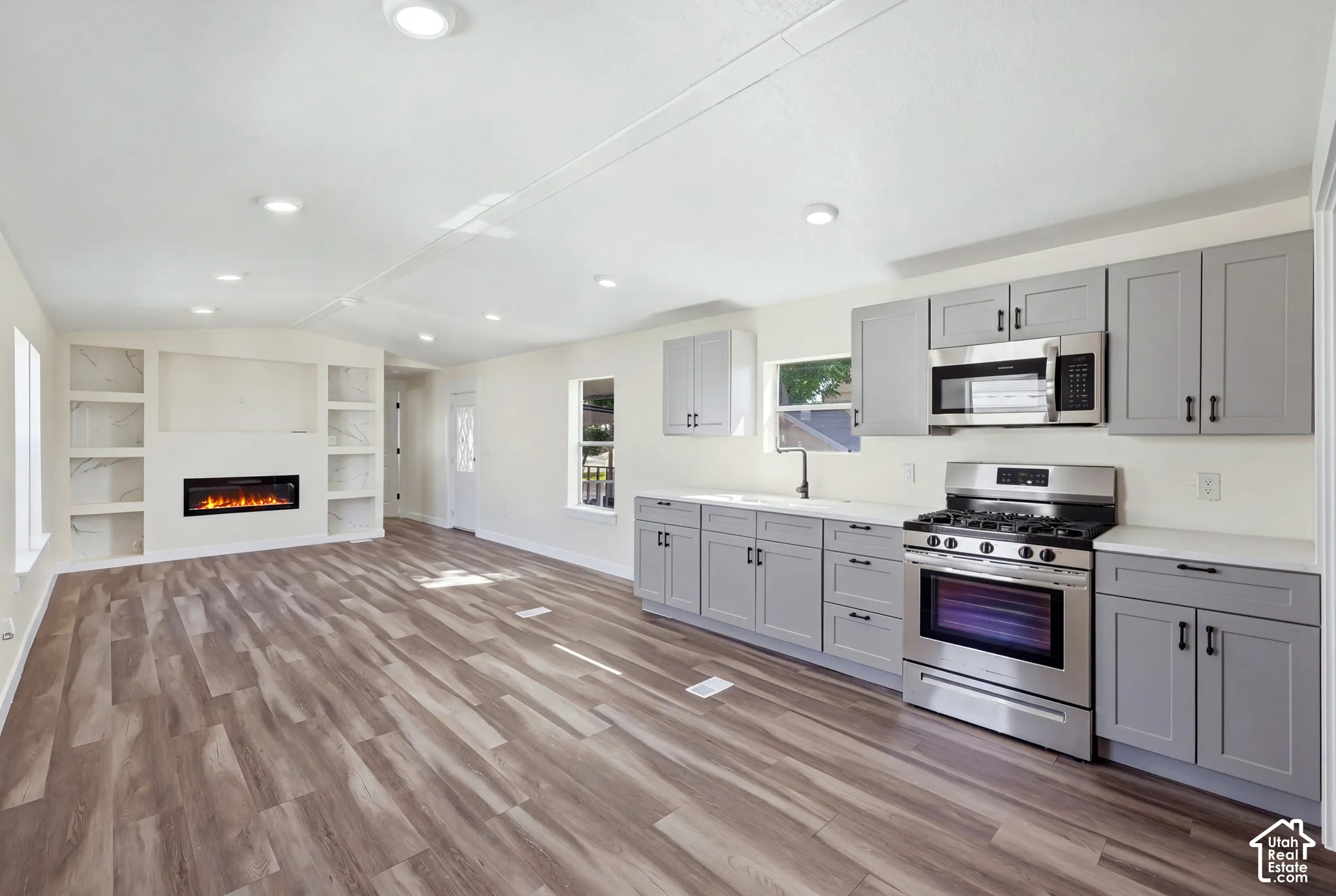 Open-concept living space with wood-finish flooring, recessed lighting, and a built-in electric fireplace
