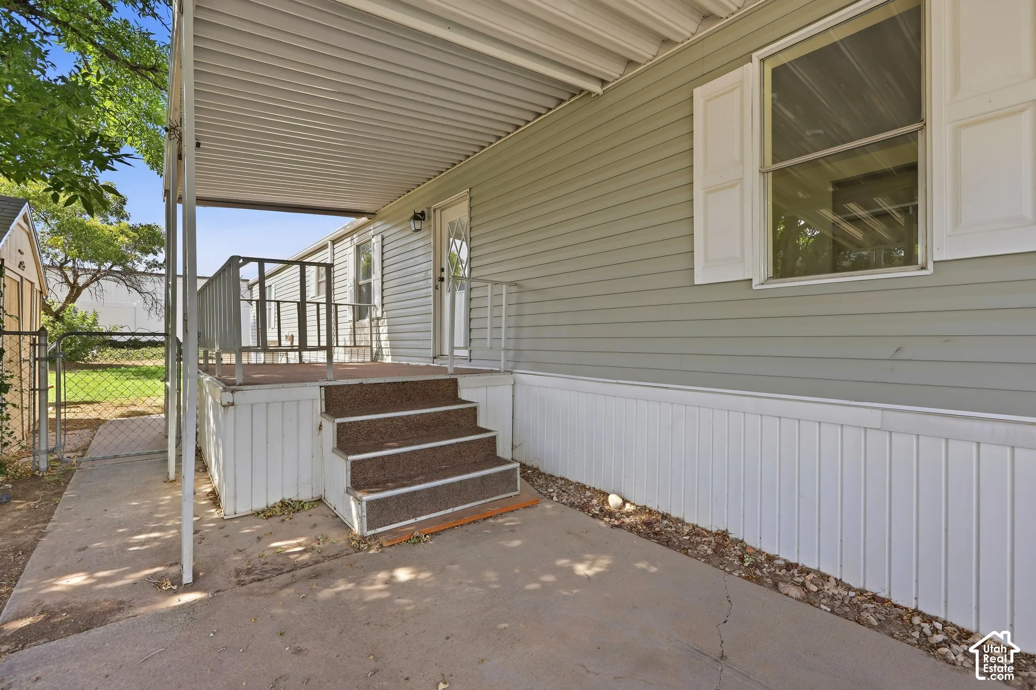 Covered concrete patio with steps leading to an elevated deck