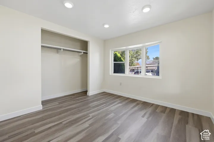 Recessed ceiling lighting, bay window, wood-finish flooring, built-in closet, and white trim
