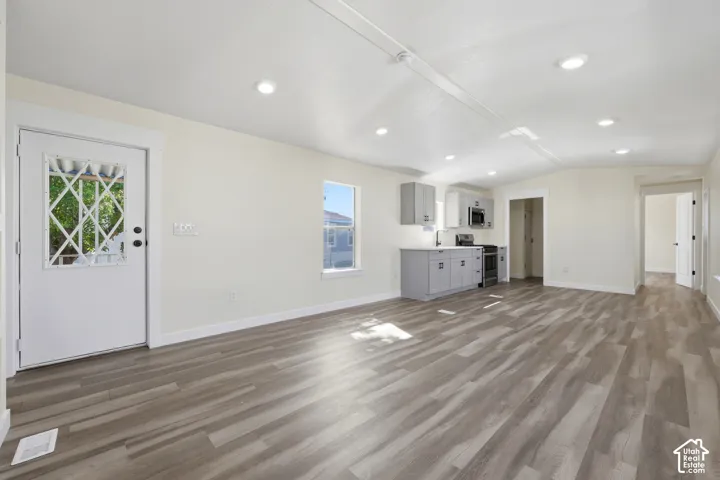 Wood-finish flooring, recessed lighting, white walls, gray cabinetry, and a white entry door with decorative glass