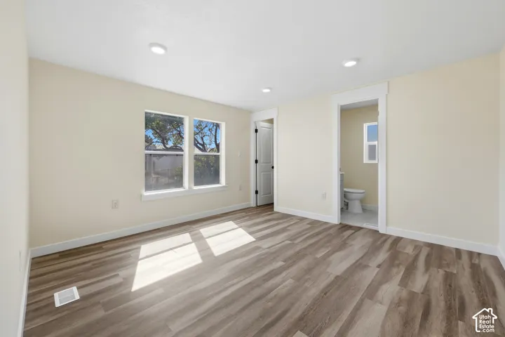 Recessed lighting, wood-finish flooring, white trim, dual windows, and an adjacent bathroom with a window