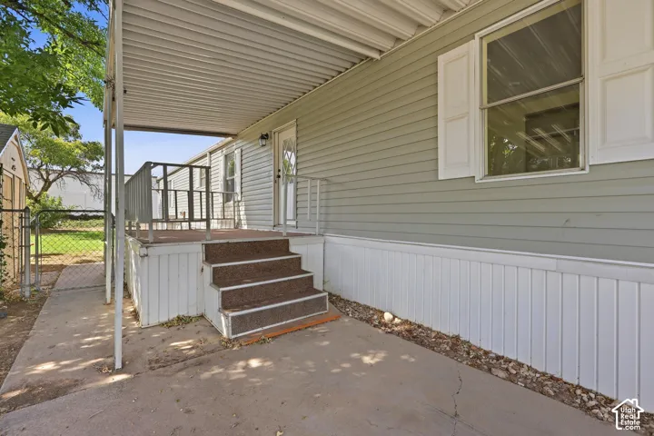 Covered concrete patio with steps leading to an elevated deck