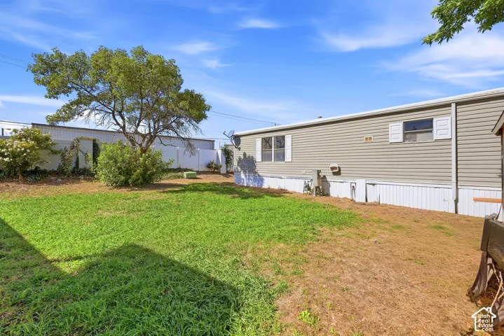 Expansive lawn area with a mature tree, bordered by a white privacy fence