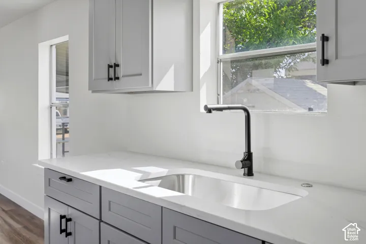 White countertops with an integrated sink, matte black faucet, and gray cabinetry