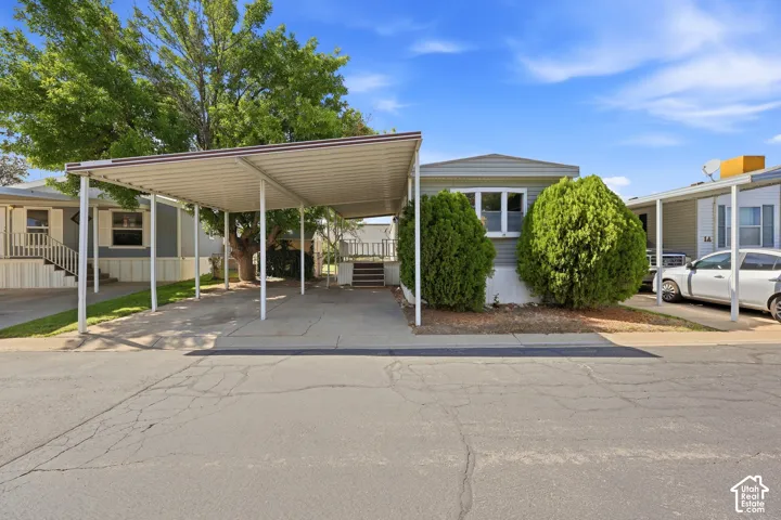 Property exterior featuring a double carport, mature trees, and established landscaping