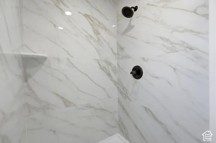 Shower featuring white marble-look wall tiling, a built-in shelf, and dark bronze fixtures