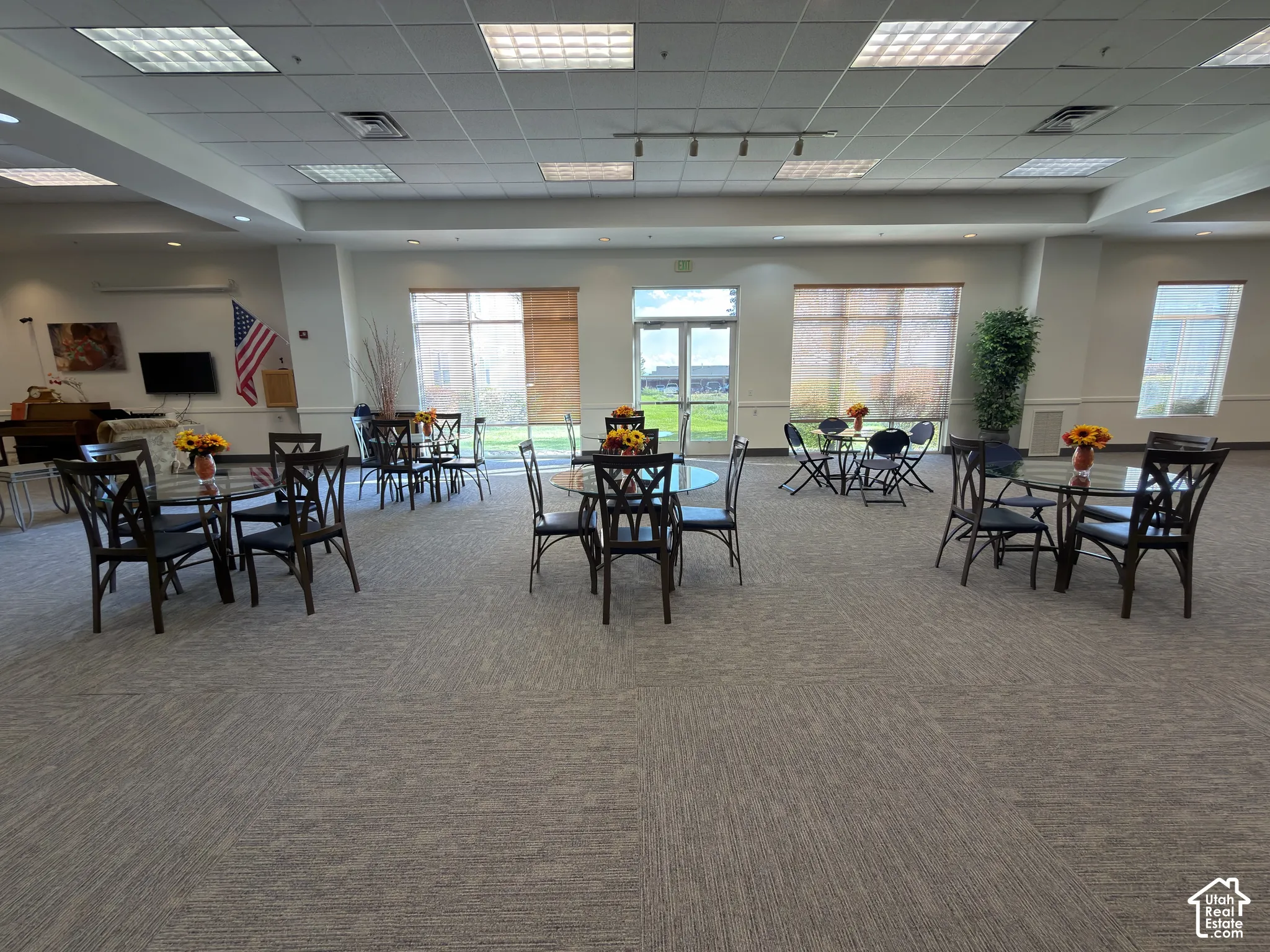 Spacious interior with tables & chairs, neutral carpeting, recessed lighting, and large windows