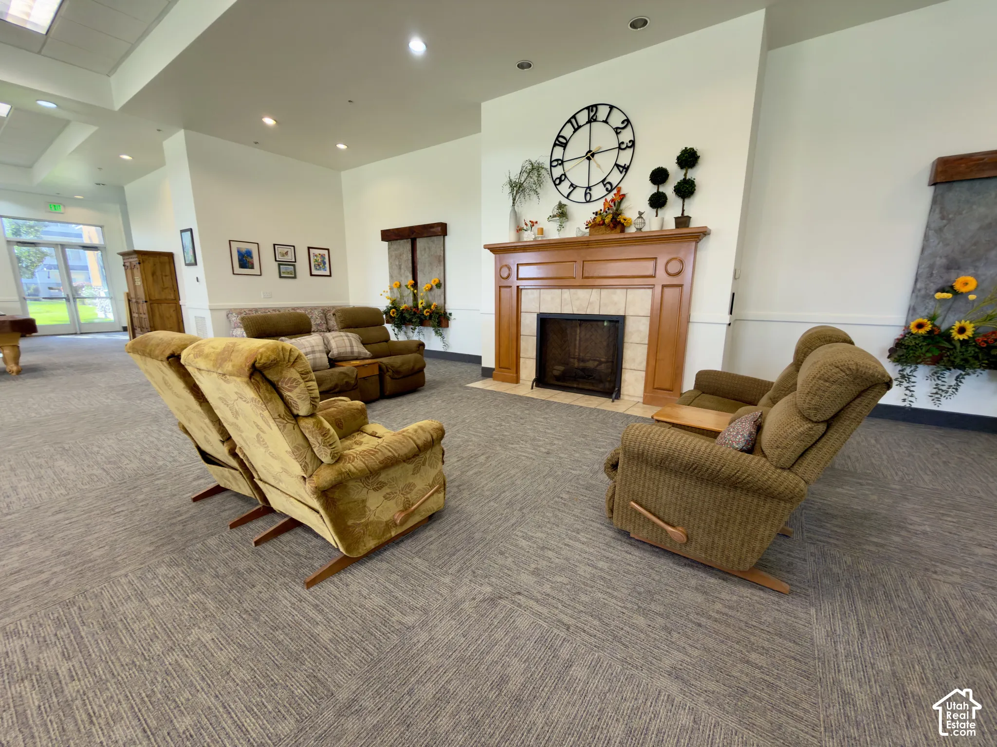 Spacious common area featuring a fireplace with a wood mantel, tiled hearth, and integrated fire screen