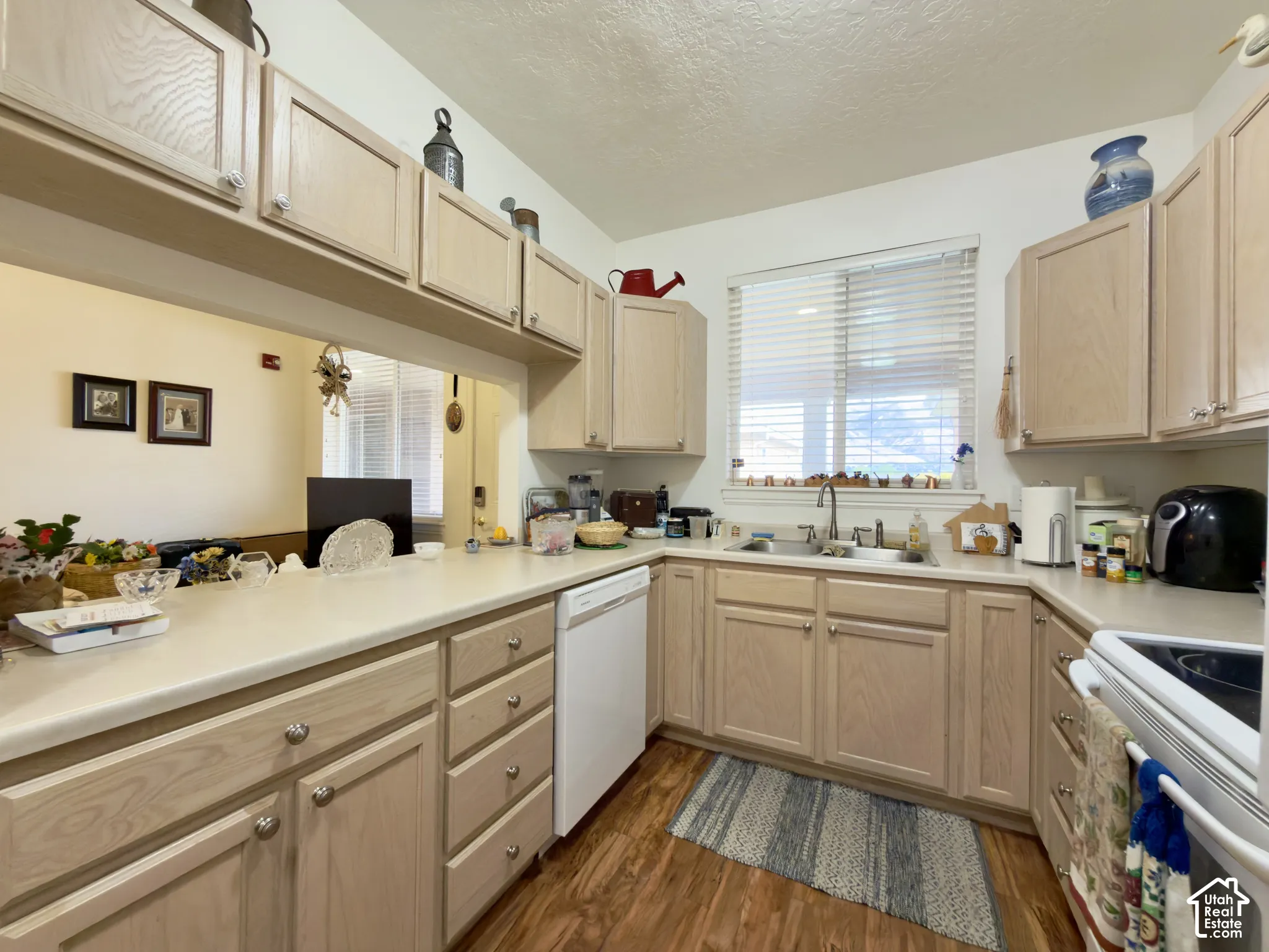 U-shaped kitchen featuring laminate flooring, light wood cabinetry, a light countertop, a double basin sink and a window with mountain views