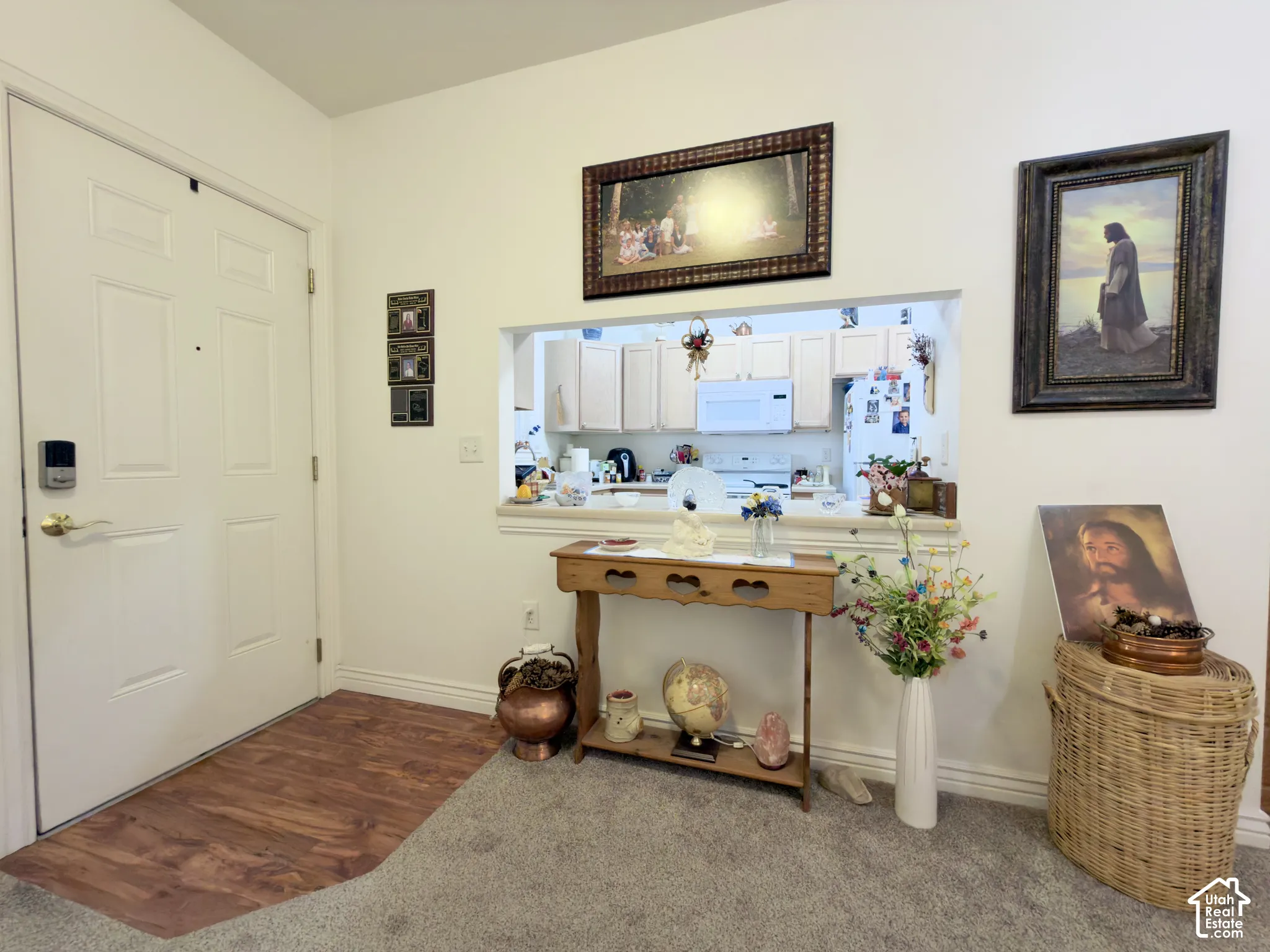 Entryway with laminate flooring, and a kitchen pass-through with off-white cabinetry