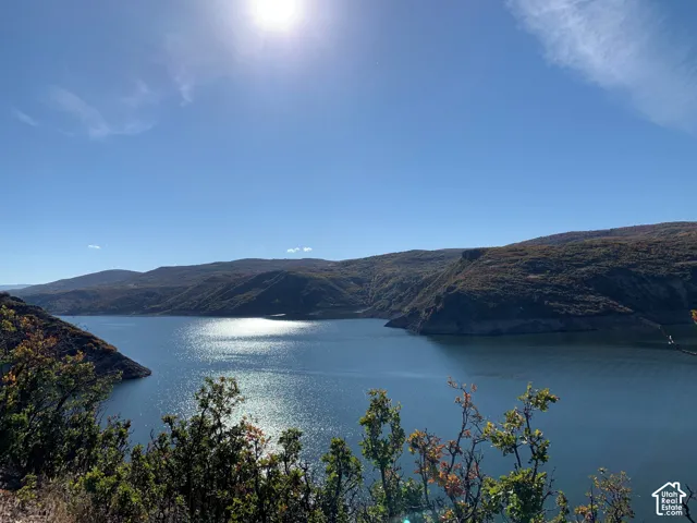 Expansive lake frontage with surrounding rolling hills and distant mountains under a clear sky