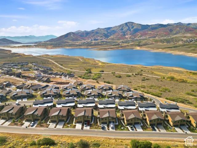 Community with multiple residences, adjacent to a large body of water, with mountainous terrain in the background