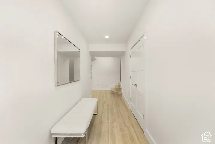 Hallway featuring wood-finish flooring, recessed lighting, and a white paneled door