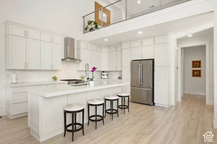 White shaker-style cabinetry, stainless steel appliances, central island with seating, tile flooring, and a unique loft overlook
