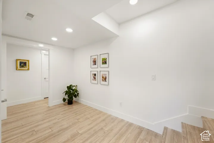 Recessed lighting illuminates the wood-finish flooring and white walls