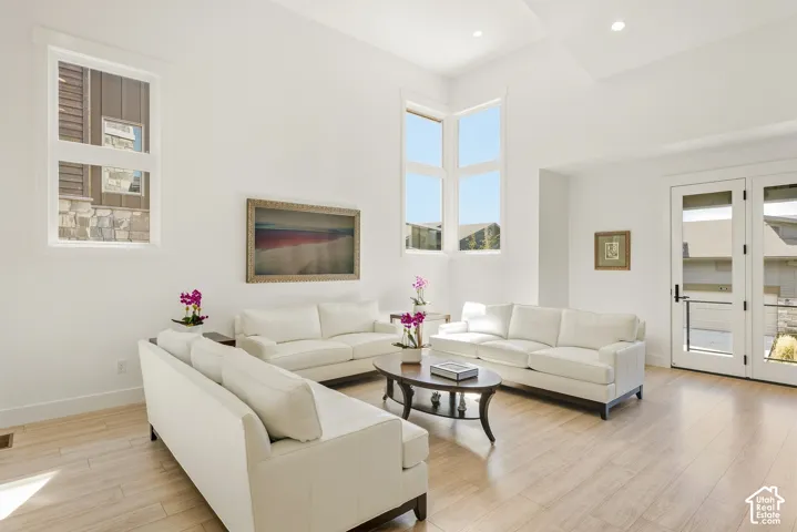 Vaulted ceiling, recessed lighting, wood-finish flooring, multiple windows, and a set of French doors