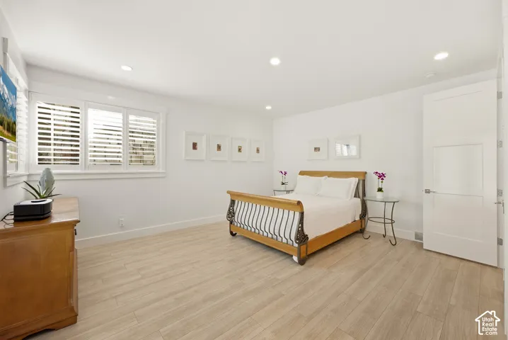 Wood-finish flooring, recessed lighting, white window shutters, and a white paneled door