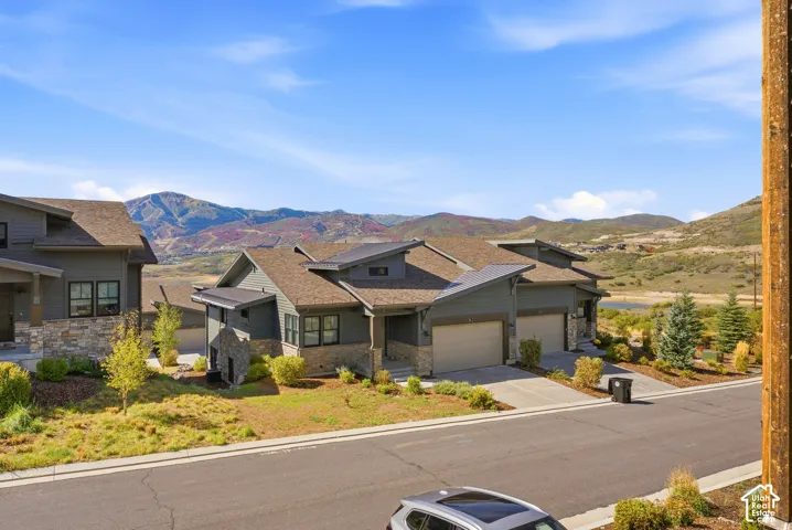 Modern architectural design with stone and siding exterior, multi-pitched rooflines, two-car garage, and established landscaping