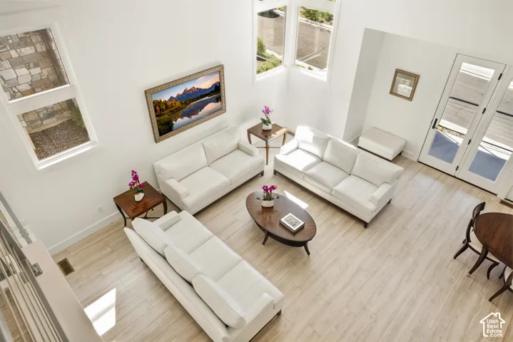 High ceilings with multiple windows, light wood-finish flooring, white walls, and French doors