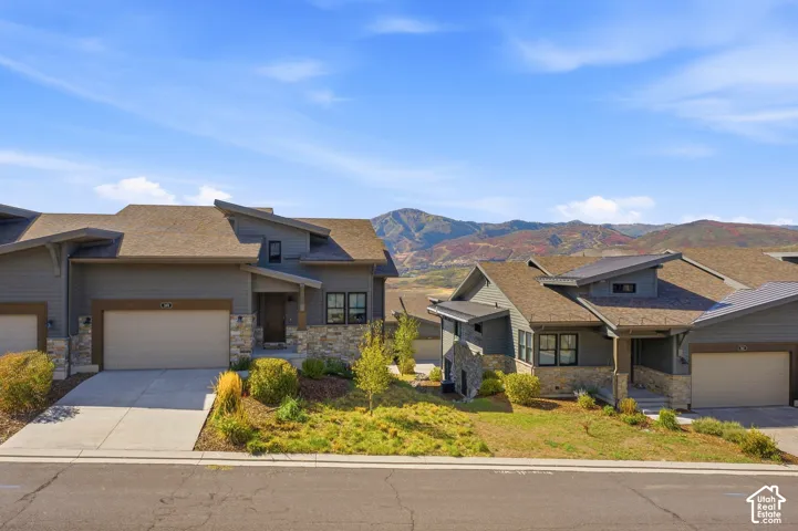 Modern exterior architecture with stone accents, attached garage, and a sloped roofline