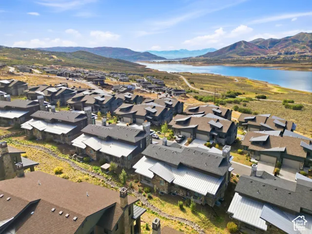 Community of multi-level properties with stone and siding exteriors, featuring attached garages, brown shingle roofs, and metal roof accents