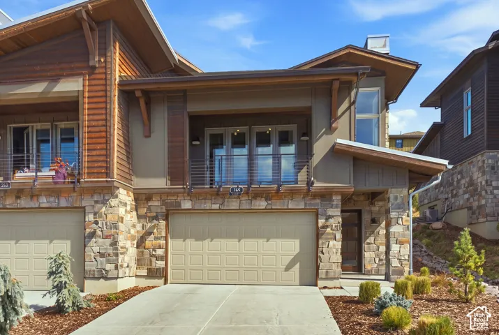 Contemporary multi-level exterior with stone veneer accents, wood siding, and an attached two-car garage