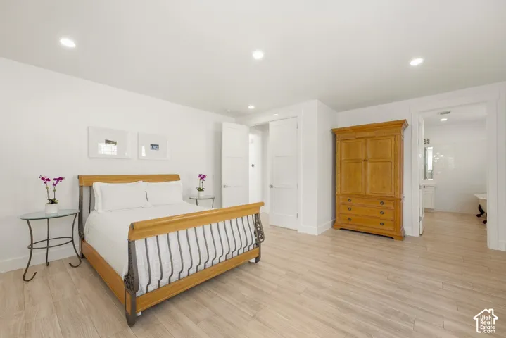 Recessed lighting, wood-finish flooring, white paneled doors, and a tiled bathroom with a freestanding tub