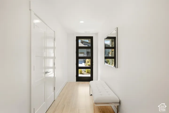 Entryway featuring wood-finish flooring, recessed lighting, white panel doors, and a dark-framed glass paneled door