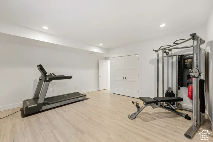 Recessed lighting, wood-finish flooring, white paneled doors, and crisp white walls