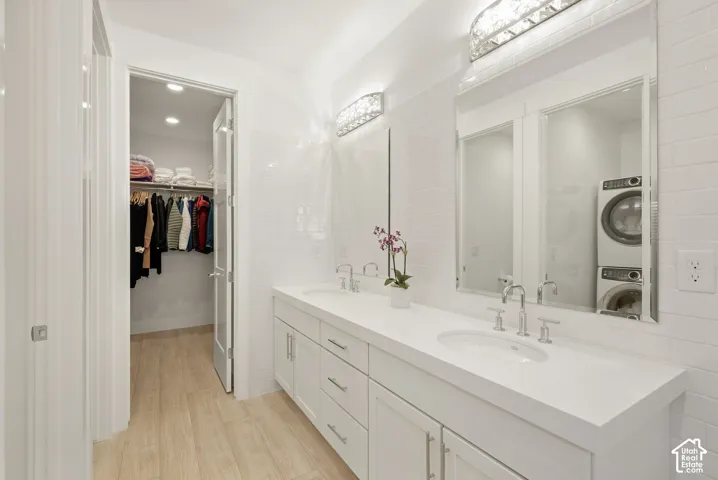 Dual vanity with integrated sinks and chrome fixtures, white tile backsplash, wood-finish flooring, and recessed lighting