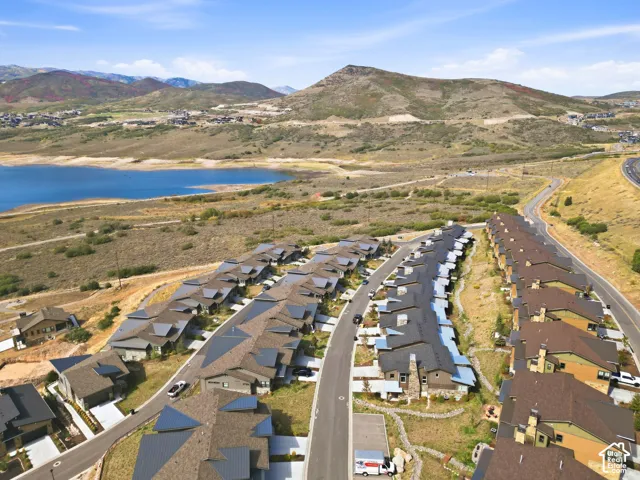 Community featuring multiple residential structures, paved roadways, and a prominent lake
