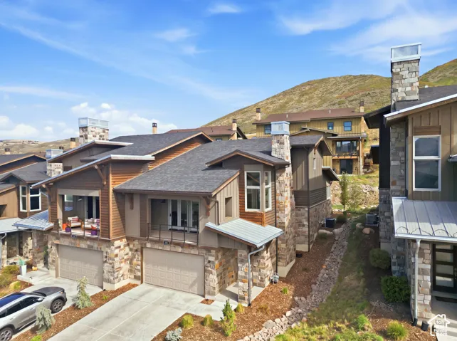 Multi-level residences featuring stone and wood siding, covered balconies, attached garages, and pitched shingle roofs
