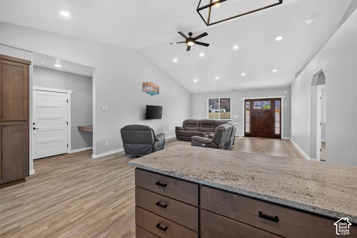 Open-concept living space featuring vaulted ceilings, recessed lighting, and wood-finish flooring