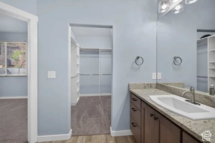 Vanity with a granite-style countertop and integrated sink, brushed nickel faucet, wood-finish cabinetry, and overhead vanity lighting