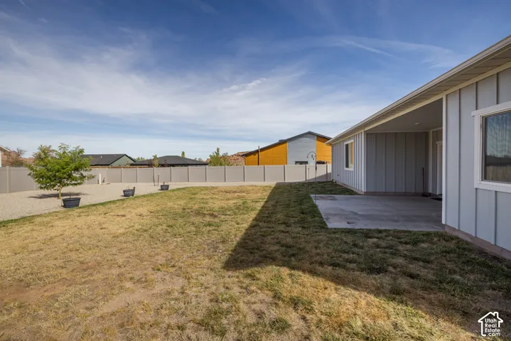 Backyard featuring a concrete patio, light gray horizontal siding, white trim, and a privacy fence