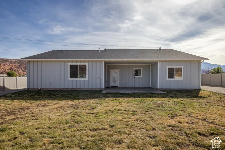 Rear exterior with a covered concrete patio, light-colored vertical siding, and a dark shingle roof