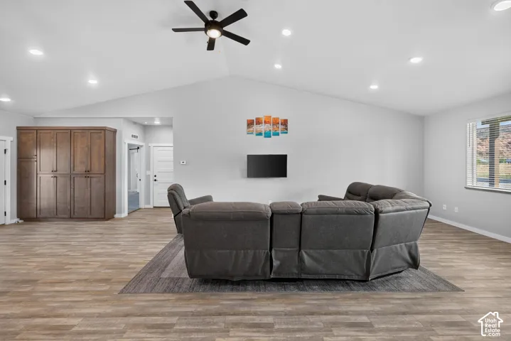 Vaulted ceiling with a ceiling fan and recessed lighting, wood-finish flooring, built-in cabinetry, and a window with blinds
