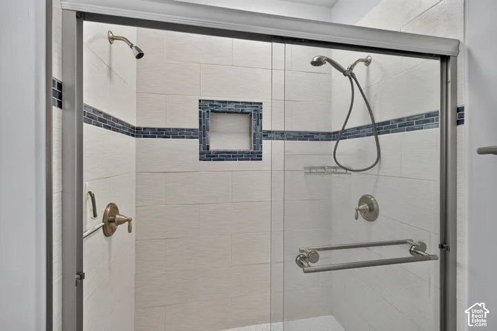 Tiled shower with glass enclosure, built-in recessed shelf, and dual showerheads