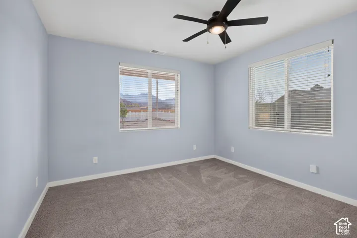 Carpeted flooring, multiple windows with blinds, ceiling fan with integrated lighting, and light blue wall finish